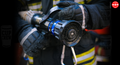 A close-up image of a firefighter's hand holding a fire hose, with the text 